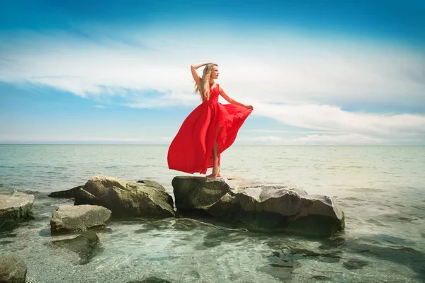 Krásná žena v zářivě červené šaty u moře. — Stock fotografie