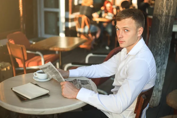 Kameraya bakarak öğle yemeğinde sokak bir kafede bir gazete okuyan adam. — Stok fotoğraf