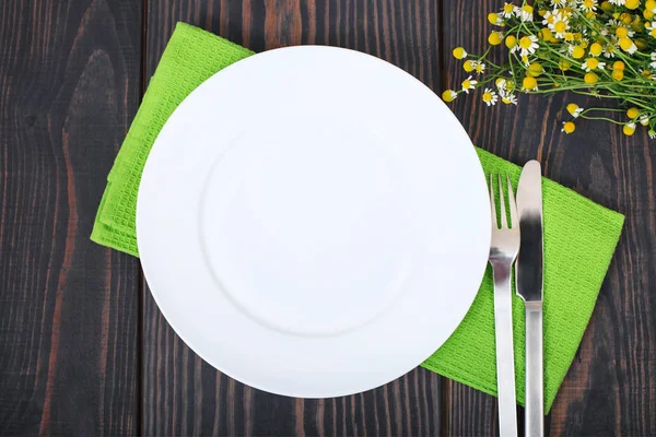 Нож, вилка и белая тарелка на зеленой салфетке . — стоковое фото