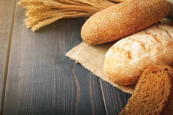 Świeży chleb i pszenica na drewnianym stole. — Zdjęcie stockowe