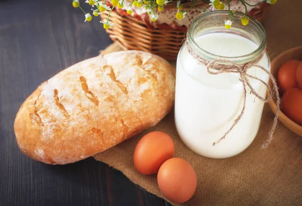 Сніданок з фермерських продуктів: яйця, молоко, хліб на дерев'яному столі . — стокове фото