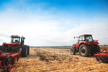 Two tractors with a plow in a field on a sunny day. clipart