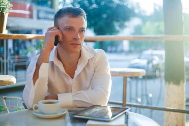 Kafede kahve içme ve telefon kullanarak genç adam.