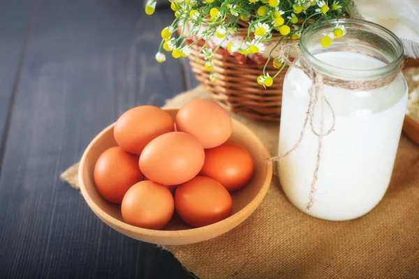 Ovos de galinha frescos e um frasco com leite na mesa da cozinha . — Fotografia de Stock