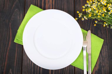 Bıçak, çatal ve beyaz plaka üzerinde yeşil bir peçete.