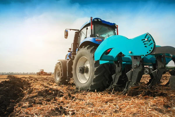 Güneşli bir günde sahada çekilir bir pulluk ile modern bir traktör.