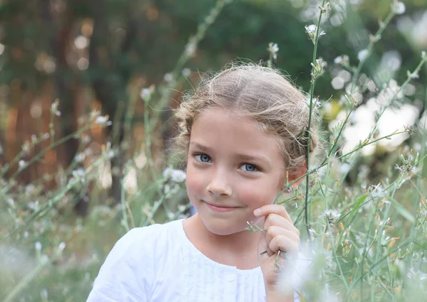 Portret van een schattig klein meisje op de natuur in bloemen. — Stockfoto