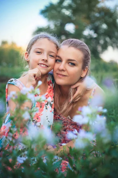 Retrato de mãe e filha na natureza em flores . — Fotografia de Stock