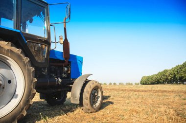 Boş bir alanda eski mavi traktör. Tarım makineleri, saha çalışması.