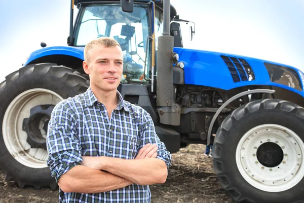 Genç çekici adamın yanına bir traktör. Tarım kavramı.