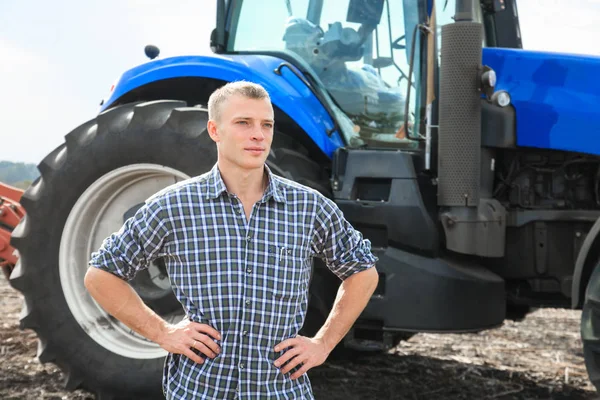 Jovem atraente perto de um trator. Conceito de agricultura . — Fotografia de Stock