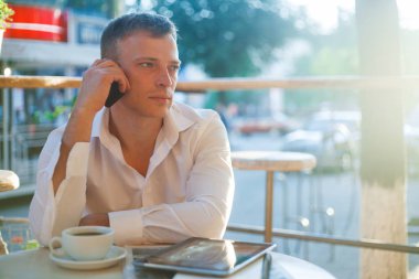 Kafede kahve içme ve telefon kullanarak genç adam.