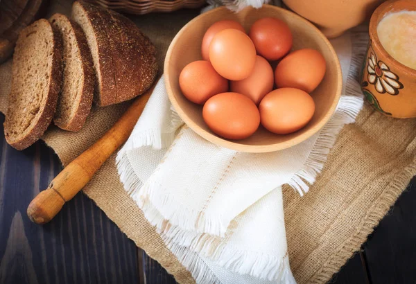 Produtos de fazenda: ovos, leite, pão em uma mesa de madeira . — Fotografia de Stock