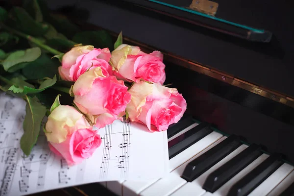 Un bouquet di rose rosa e note sulla tastiera del pianoforte . — Foto Stock