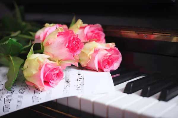 Ένα μπουκέτο από τριαντάφυλλα ροζ και νότες στο πιάνο πληκτρολόγιο. — Φωτογραφία Αρχείου