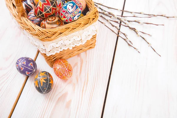 Ovos de Páscoa em uma cesta no fundo da prancha branca . — Fotografia de Stock