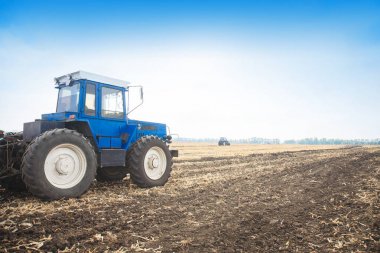 Boş bir alanda eski mavi traktör. Tarım makineleri, saha çalışması.