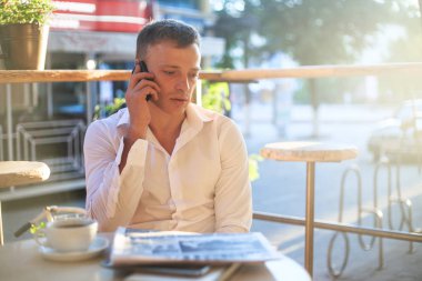 Kafede kahve içme ve telefon kullanarak genç adam.