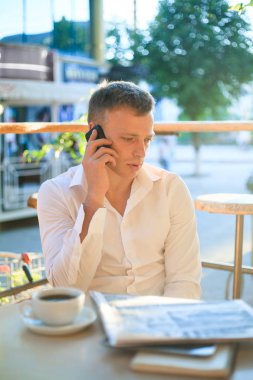 Kafede kahve içme ve telefon kullanarak genç adam.