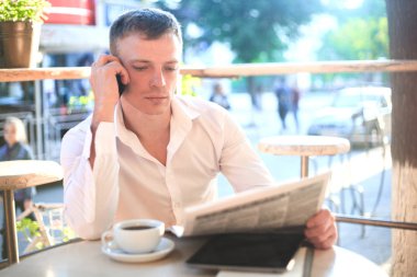 Kafede kahve içme ve telefon kullanarak genç adam.