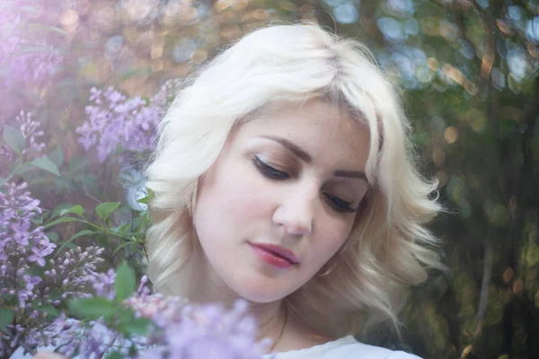 Bella donna in un giardino primaverile con lilla in fiore . — Foto Stock
