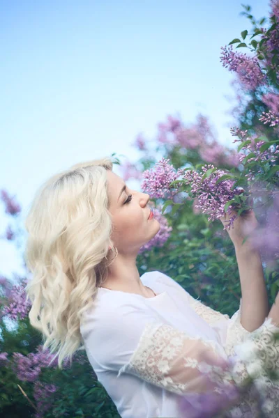 Bella donna in un giardino primaverile con lilla in fiore . — Foto Stock
