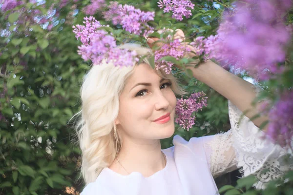 Bella donna in un giardino primaverile con lilla in fiore . — Foto Stock