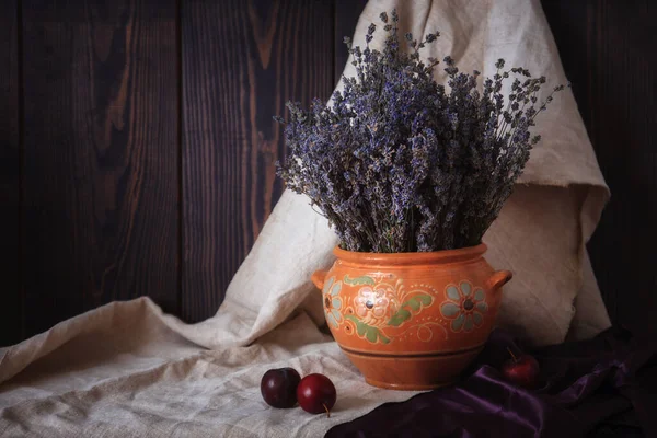 Stilleben med lavendel i en lerkruka och plommon på bordet. — Stockfoto