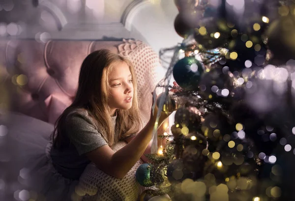 在一棵长着花环的圣诞树前，一个快乐可爱的女孩的画像。 新年假期. — 图库照片