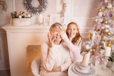 Güzel genç anne kızıyla birlikte yılbaşı ağacının yanındaki masada..