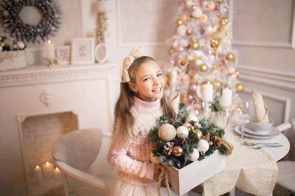 Merry Christmas celebration. Beautiful little girl in a dress lying near the Christmas tree. Winter holidays.