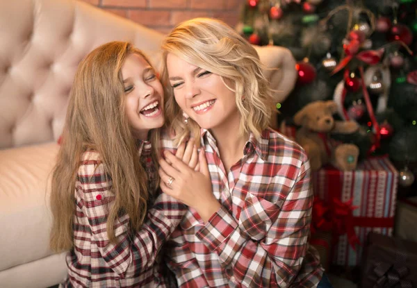 Portret van een vrolijke moeder en dochter tegen de achtergrond van het kerstinterieur. — Stockfoto