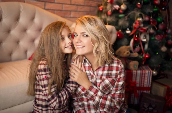 Portret van een vrolijke moeder en dochter tegen de achtergrond van het kerstinterieur. — Stockfoto