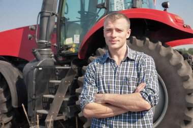 Genç çekici adamın yanına bir traktör. Tarım kavramı.