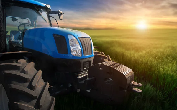 日没時に緑の小麦とフィールド上の近代的なトラクター. — ストック写真