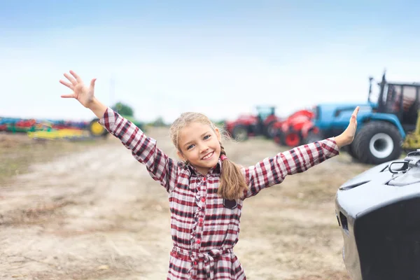 Милая девушка рядом с современным трактором в поле . — стоковое фото