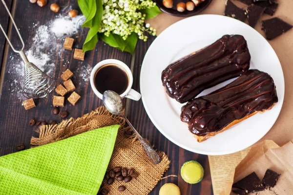 Fresh homemade eclairs with chocolate on the kitchen table. French pastries. — ストック写真