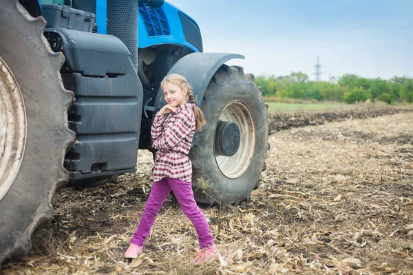 Милая девушка рядом с современным трактором в поле . — стоковое фото