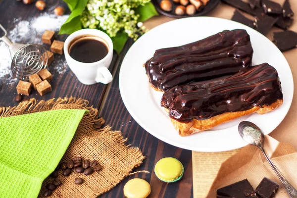 Fresh homemade eclairs with chocolate on the kitchen table. French pastries. — ストック写真