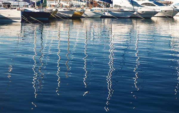 Reflexão de mastros de iate sobre a água no porto . — Fotografia de Stock