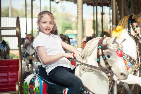 A girl riding a toy horse on a carousel in the park. — Stock Photo, Image