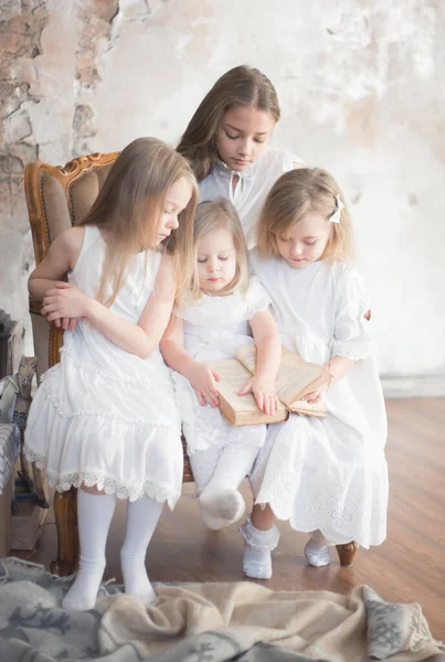 Four girls friends or sisters read a book at home. Retro style.