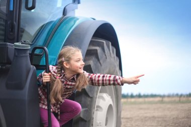 Tarladaki modern traktörün yanında tatlı bir kız..