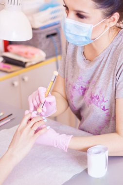 Manikürcü kuaförde manikür yapıyor..