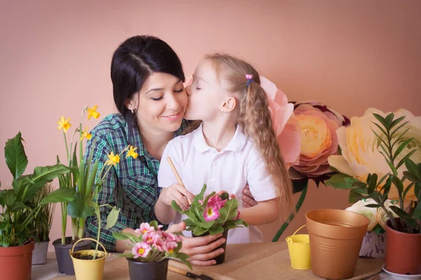 Schattig kind meisje helpt haar moeder om de zorg voor planten. — Stockfoto
