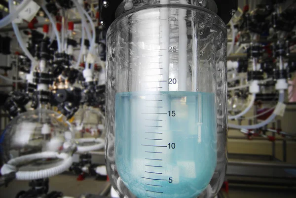 Herstellung von Medikamenten in einer Arzneimittelfabrik. blaue Flüssigkeit in einem Kolben — Stockfoto