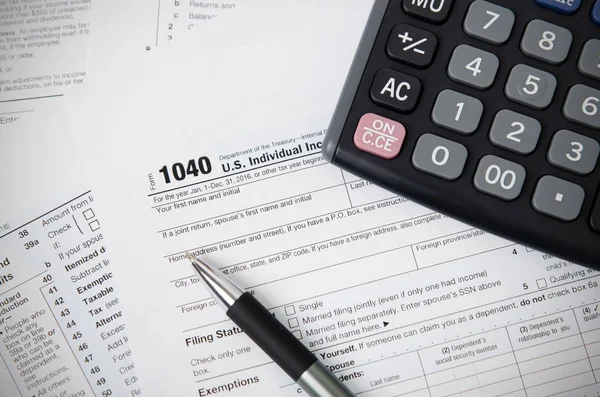 Налоговая форма США 1040 с ручкой и калькулятором — стоковое фото