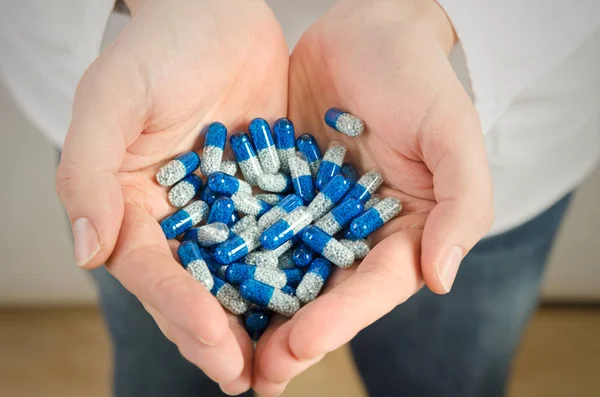 Homem segura uma pilha de comprimidos em uma palma — Fotografia de Stock