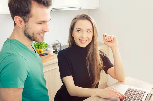 Couple uses the computer in the kitchen
