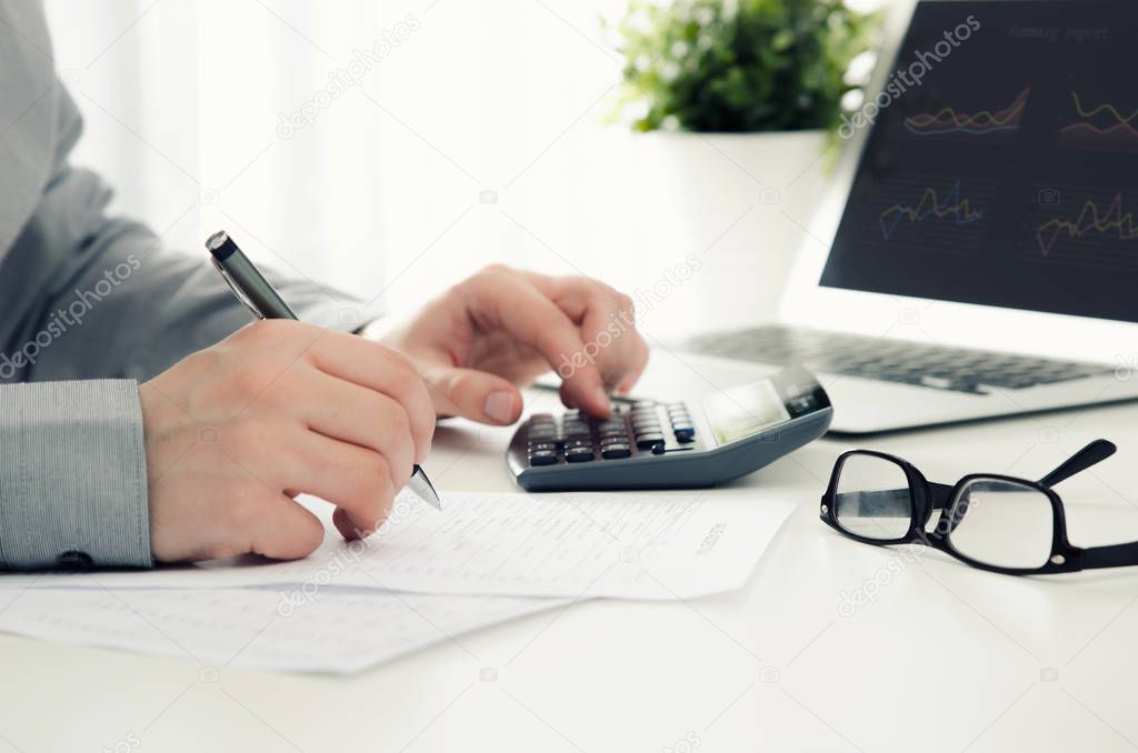 Businessman working in office with calculator